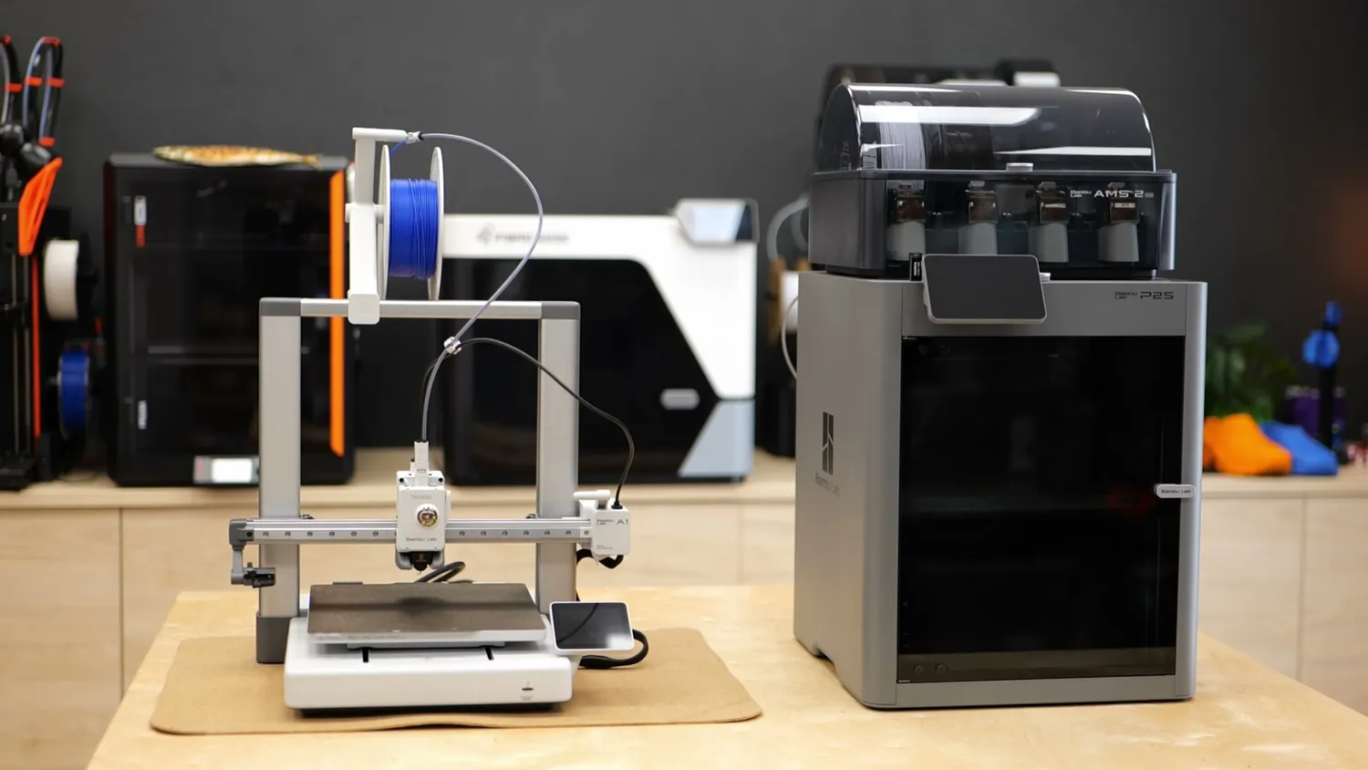 Open-frame 3D printer next to an enclosed CoreXY 3D printer
