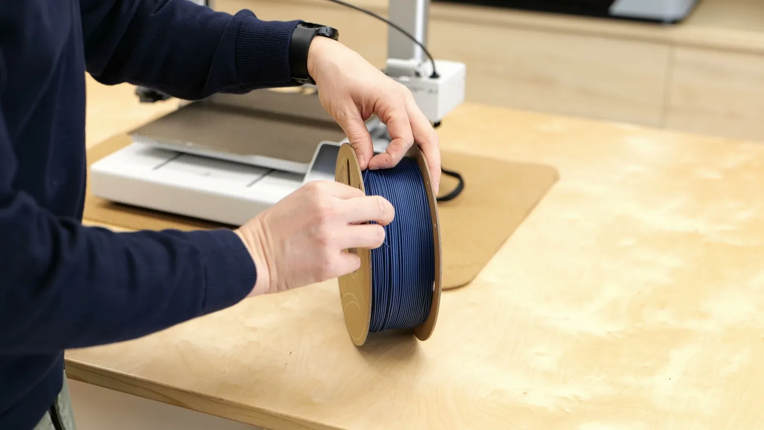 Hand holding the loose end of a filament spool