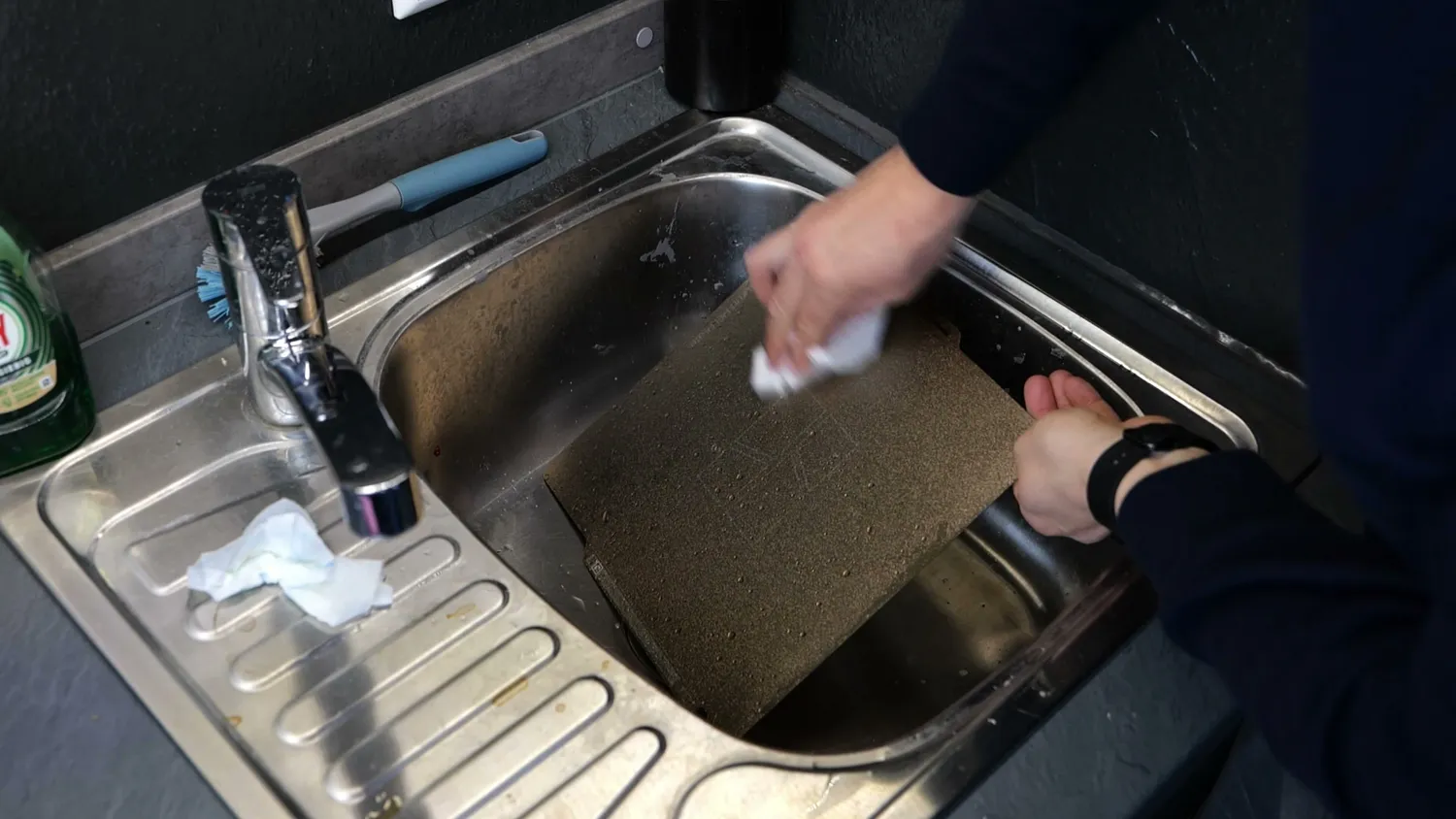 Build plate being scrubbed in a kitchen sink with dish soap