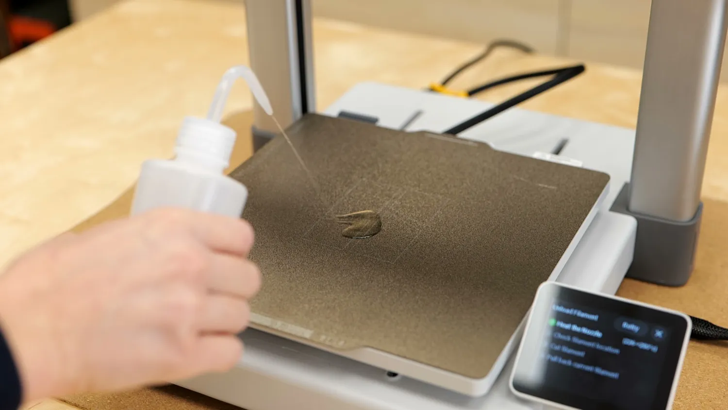 Isopropyl alcohol being squirted onto a dirty 3D printer build plate
