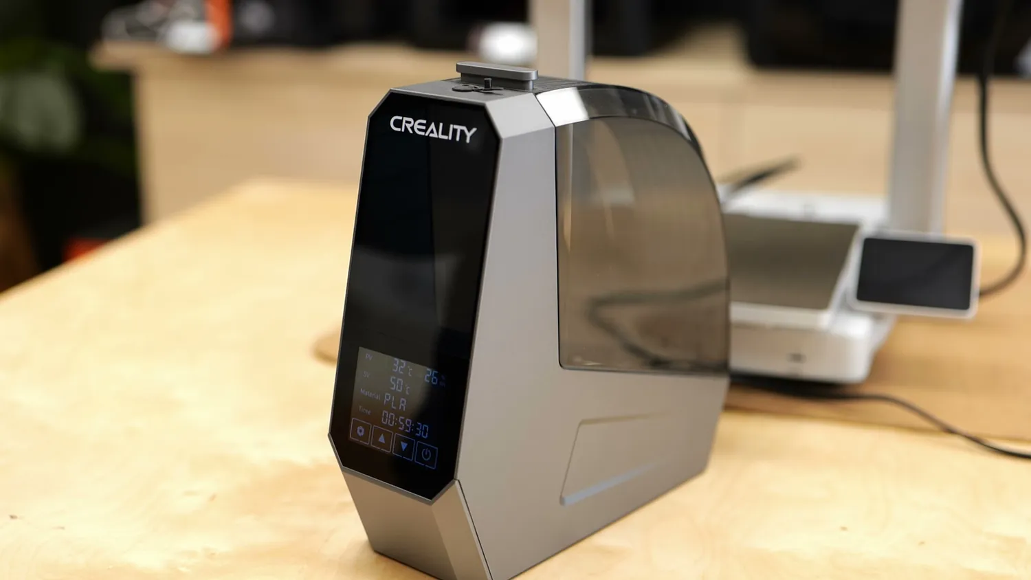 Filament dryer standing on a workbench next to a 3D printer