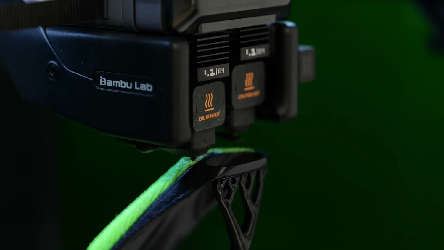 Bambu Lab dual-nozzle toolhead printing a green and black part