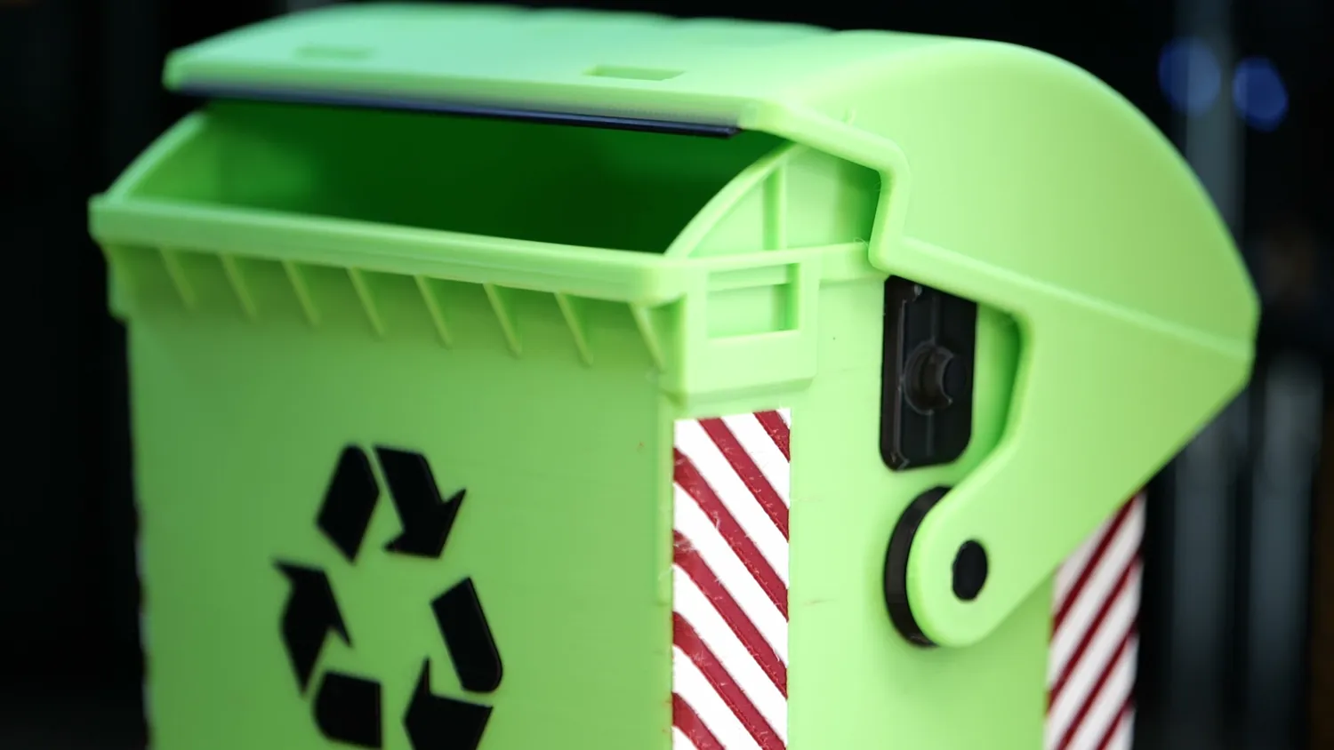 A lime-green wheelie bin model with a black recycling logo and red-and-white hazard stripes, the multi-colour edges crisp