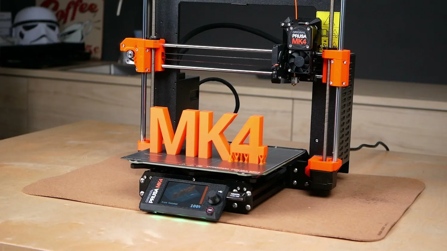 Prusa MK4 with a large orange MK4 logo printed on the bed